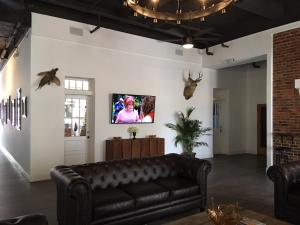 圣克卢亨特阿姆斯酒店的客厅配有真皮沙发和墙上的电视