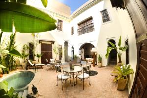 马拉喀什阿莫尼特Spa庭院旅馆的一个带桌椅的户外庭院和一个游泳池