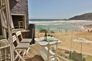赫罗德斯湾Oupa se Pitte的一个带桌椅和海滩的阳台