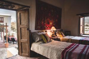 卡奇Casa del Tejedor的一间卧室设有两张床,墙上挂着一幅画