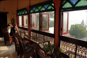 瓦拉纳西Sahi River View Guest house的一群人坐在桌子上,从窗户望出去
