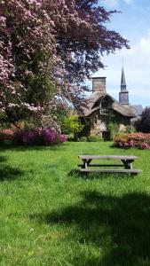 Saint-Symphorien-des-MontsLa Tiny du Parc : Saint Symphorien des Monts的坐在建筑物前面的草上的一个长凳