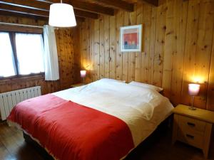 斯姿Chalet Des Sangliers的一间卧室配有一张带红白毯子的床
