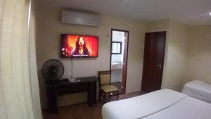 瓜吉鲁Ruan Beach的卧室配有一张床,墙上配有电视。