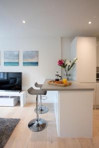 温莎Hampden Apartments - The George的白色的厨房配有桌子和电视。