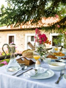 斯塔夫鲁波利To Archontiko Guesthouse Villa的一张桌子,上面有白色的桌布,布上有食物和鲜花
