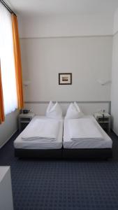 黑灵斯多夫幸运酒店的一间卧室设有两张白色的床和窗户