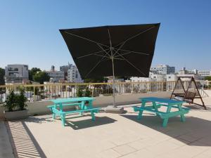 尼科西亚NEX Hostel的屋顶上设有两张野餐桌和一把雨伞