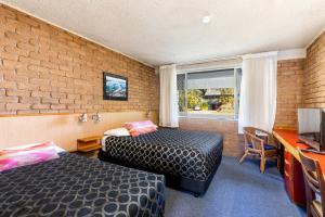 科夫斯港阿曲亚吉汽车旅馆的一间设有两张床和砖墙的房间