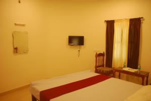 根尼亚古马里Hotel Jebasakthy的卧室配有一张床,墙上配有电视。