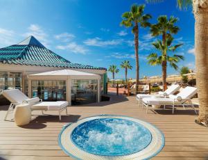 科斯塔卡玛H10 Playa Esmeralda - Adults Only的一个带游泳池、椅子和棕榈树的甲板