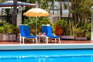 拉克鲁斯唐玛诺利透酒店的游泳池旁的两把椅子和一把遮阳伞