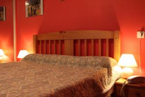 蓬托尔松Logis Hôtel et Restaurant La Tour Brette的一间卧室配有一张红色墙壁的床和两盏灯。