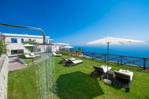 阿杰罗拉Villa Paradise Resort的后院设有喷泉、椅子和遮阳伞