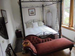 金尤西Avondale House的一间卧室配有一张四柱床和一张红色沙发
