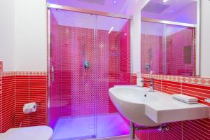 阿杰罗拉Villa Paradise Resort的浴室设有水槽和粉红色瓷砖淋浴。