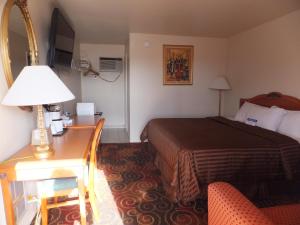 圣罗莎Americas Best Value Inn Santa Rosa, New Mexico的酒店客房配有一张床和一张带台灯的书桌