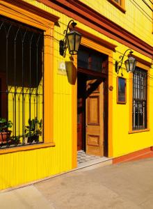 瓦尔帕莱索阿康特拉鲁精品酒店 的黄色的建筑,带有木门和街道