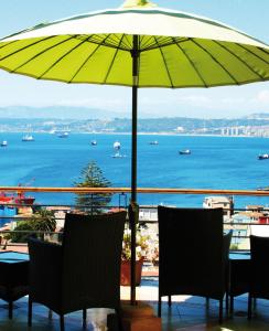 瓦尔帕莱索阿康特拉鲁精品酒店 的阳台的遮阳伞下的桌椅