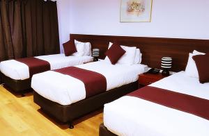 奥克兰机场花园会议中心酒店的酒店客房,设有三张床,配有白色和红色的床单