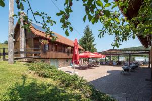雷布尼克Hotel Srakovcic Heart of Nature的一座配有红色雨伞和桌椅的建筑