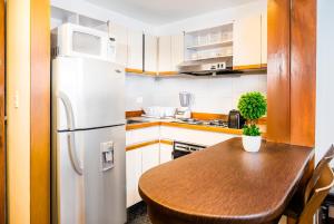 波哥大劳埃德公园93公寓套房酒店的厨房配有白色冰箱和木桌