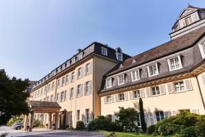 柯尼希斯温特Steigenberger Grandhotel & Spa Petersberg的棕色屋顶的大型棕褐色建筑