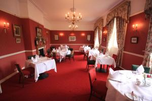 Hovingham卫斯利安酒店的餐厅配有白色的桌椅和吊灯