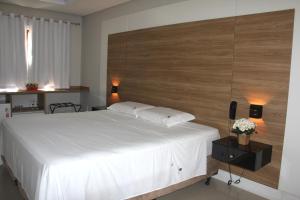 弗洛里亚诺波利斯Chalés Saint Germain的卧室配有白色的床和木制床头板