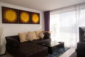 拉迈热带海景公寓的客厅配有黑色真皮沙发和电视