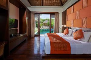 沙努尔玛哈吉瑞萨努尔别墅酒店的一间卧室配有一张床、一台电视和一个游泳池