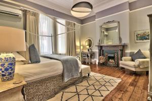 开普敦Parker Cottage Guesthouse的一间卧室配有一张床、一个壁炉和一个镜子