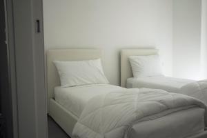阿科Residenza Cinisca的卧室内的两张床,配有白色床单和枕头