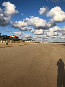卡德赞德Familie beachhuis op de duinen (Duinhuis)的站在海滩上的一个人的影子