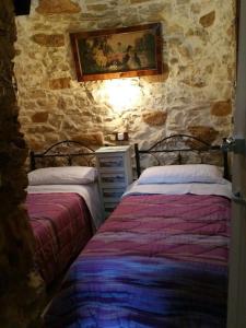 科拉托trulli di piano mangieri的一间卧室设有两张床和石墙