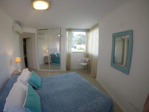 埃斯特角城Wind Tower的一间卧室配有蓝色的床和镜子