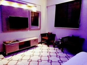 卡拉奇Diplomat Inn Hotel的客厅配有2把椅子和平面电视