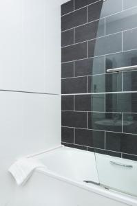 圣赫利尔泽西海浪酒店的浴室设有玻璃淋浴间和黑色瓷砖墙