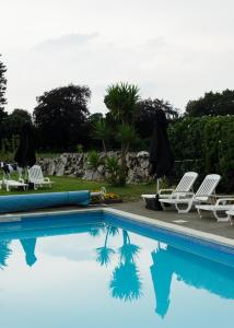 圣赫利尔泽西海浪酒店的一个带两把草坪椅和遮阳伞的游泳池