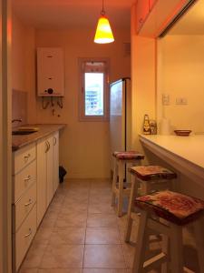 布兰卡港Departamento Temporario Bahia Blanca的厨房配有白色橱柜和凳子