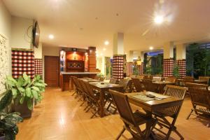 库塔芒加尔印尼酒店的一间带木桌椅的餐厅和一间酒吧