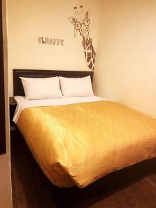 台东假期商务旅馆的卧室内的一张床位,墙上有长颈鹿