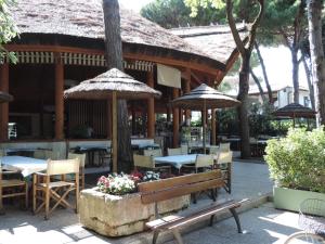 丽都斯皮纳Victoria Mobilehome in Camping Mare e Pineta的餐厅设有长凳、桌子和遮阳伞
