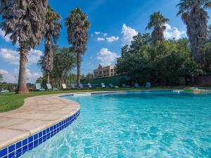 穆德斯蒂夫格林伯恩洛奇Spa酒店的棕榈树游泳池和背景房屋