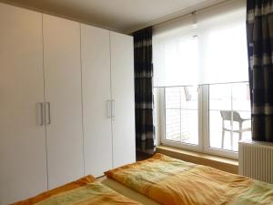 万根沃格Villa Marina Wangerooge的卧室配有白色橱柜、床和窗户。