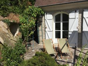 瓦兹河畔欧韦La maison du lac的两把椅子坐在房子前面的庭院