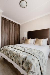 米德兰Kyalami Creek的一间卧室配有一张大床和木制床头板