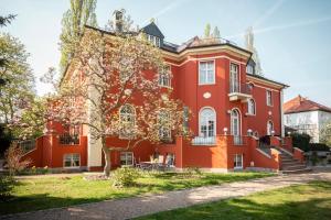 德累斯顿Villa am Park Apartment的前面有一棵树的红色房子