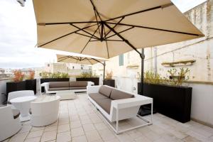 卡萨拉诺维科雷吉奥酒店的庭院配有大遮阳伞和桌椅