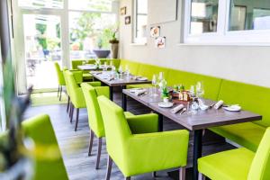 埃根斯泰因-列奥波德港Hotel Löwen的餐厅的一排桌子和绿色椅子